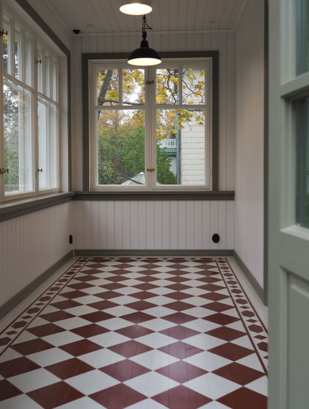 Restaurerad glasveranda i Koskela med spröjsade fönster och rutigt klinkergolv
